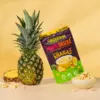 Gefriergetrocknete Ananas-Snacks von Nutripur neben einer frischen Ananas und einer Schale mit Trockenfrüchten.
