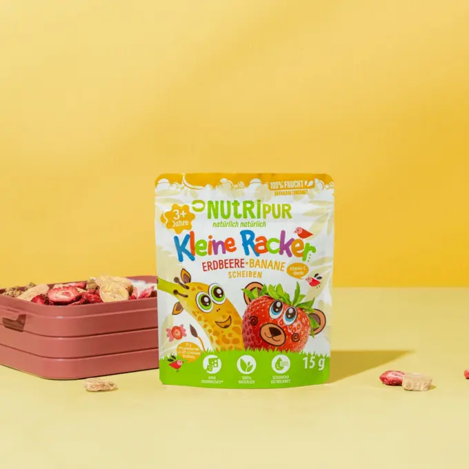 Bild zeigt die kleinen Racker der Sorte Erdbeere und Banane von Nutripur mit Verpackung und Brotdose