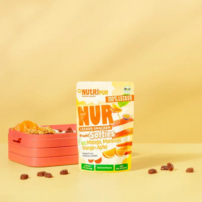 Bild zeigt die NUR Frucht Softies BIO Mango, Maracuja, Orange & Apfel mit Verpackung und Brotdose